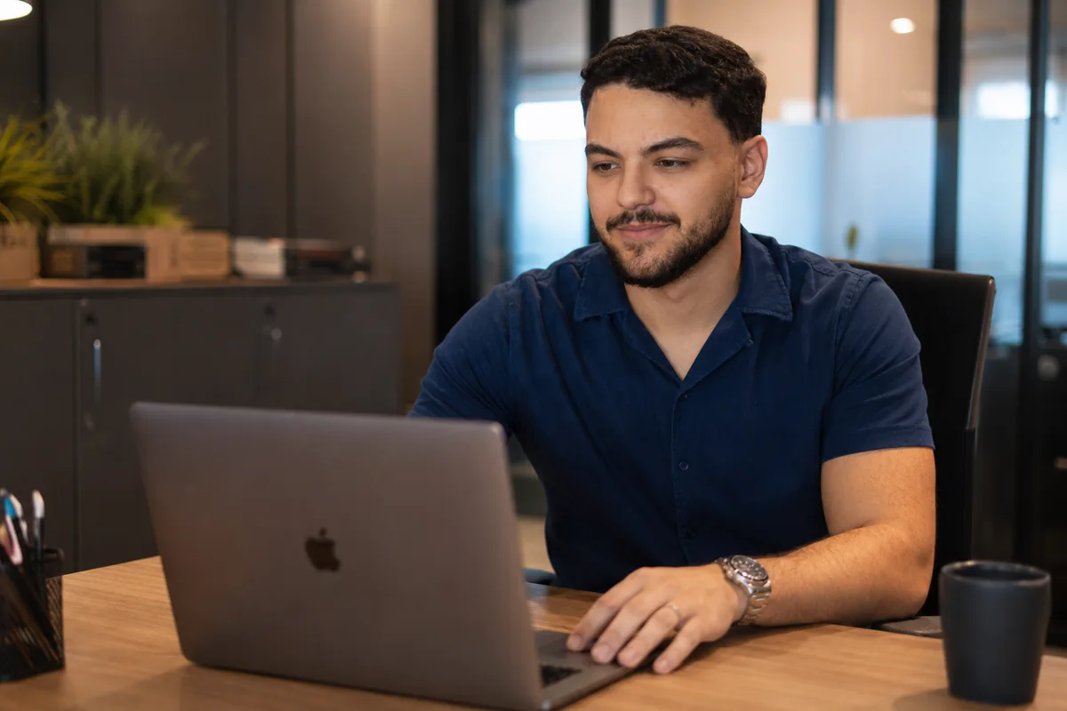 Matheus Augusto trabalhando em um notebook no escritório